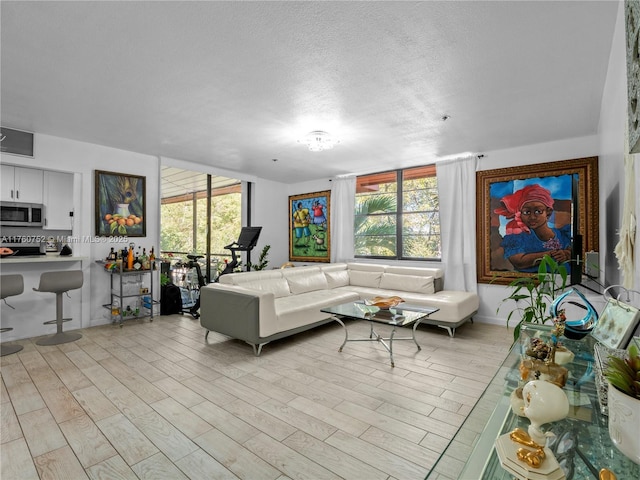 living area featuring light wood-type flooring, a wealth of natural light, and a textured ceiling