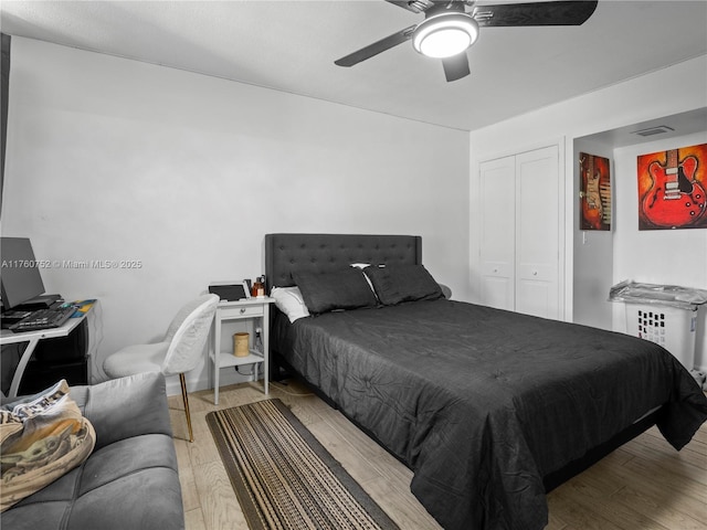 bedroom with a ceiling fan, visible vents, wood finished floors, and a closet