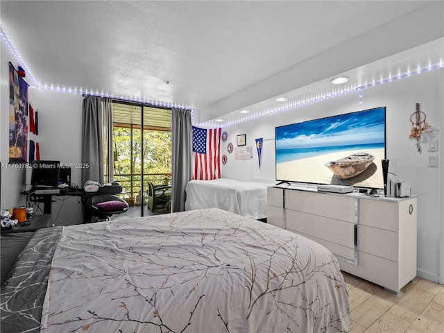 bedroom featuring access to exterior, light wood-style flooring, and a textured ceiling