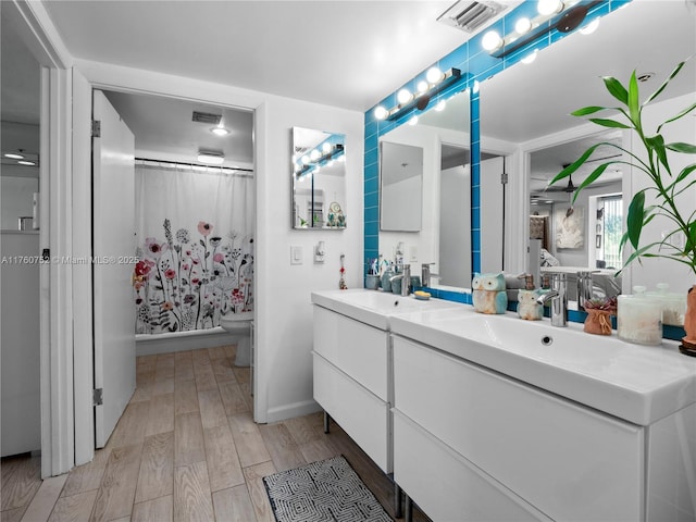 bathroom with double vanity, visible vents, wood finished floors, and a sink