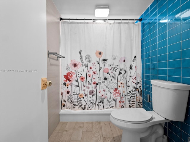 full bathroom with a shower with curtain, tile walls, toilet, and wood finished floors