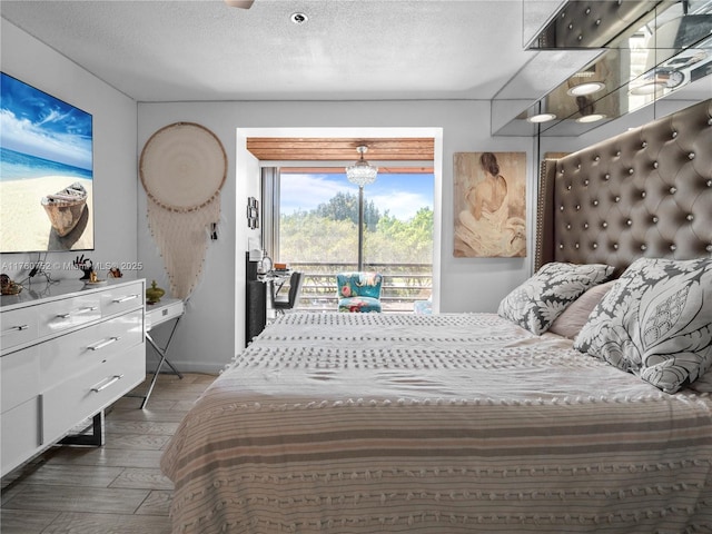 bedroom featuring wood finished floors, a textured ceiling, and access to outside