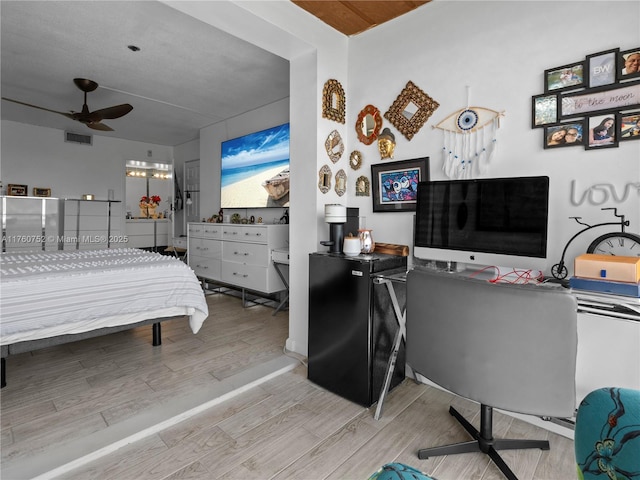 bedroom with visible vents, black refrigerator, and wood finished floors