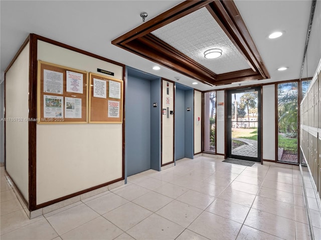 spare room with light tile patterned floors, a raised ceiling, elevator, and ornamental molding