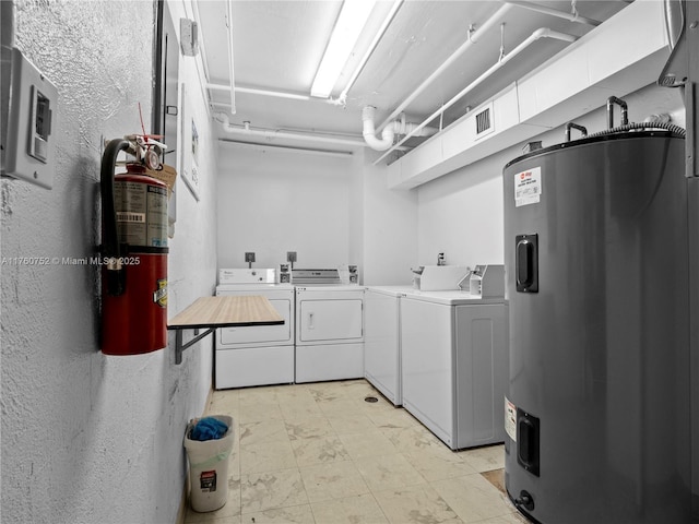 clothes washing area with water heater, visible vents, a textured wall, and separate washer and dryer