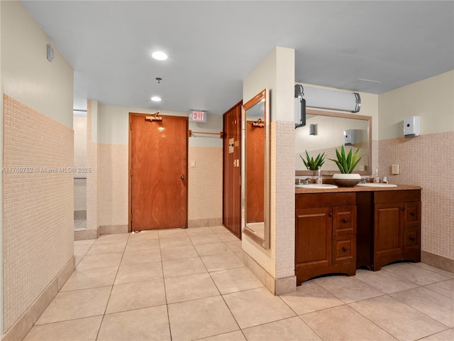 hallway featuring a sink, wainscoting, and light tile patterned floors