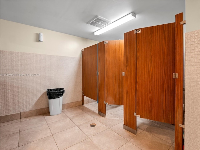 bathroom with tile patterned floors, visible vents, tile walls, and wainscoting