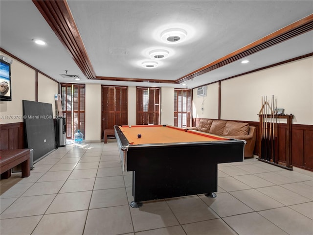 game room with a tray ceiling, ornamental molding, wainscoting, light tile patterned flooring, and billiards