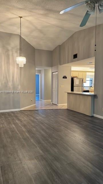 unfurnished living room with visible vents, baseboards, dark wood finished floors, and ceiling fan with notable chandelier