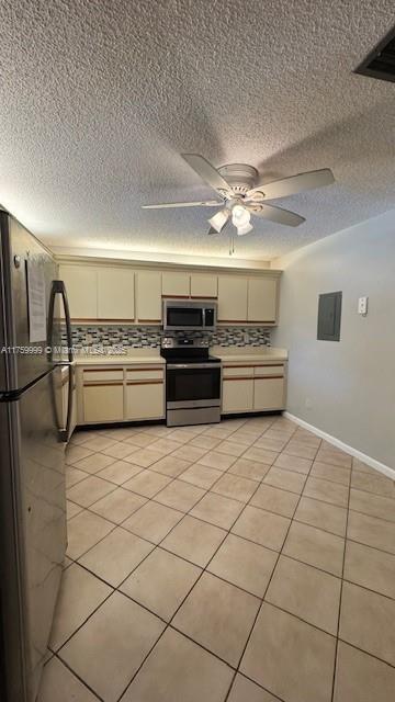 kitchen featuring cream cabinetry, tasteful backsplash, stainless steel appliances, light tile patterned flooring, and light countertops