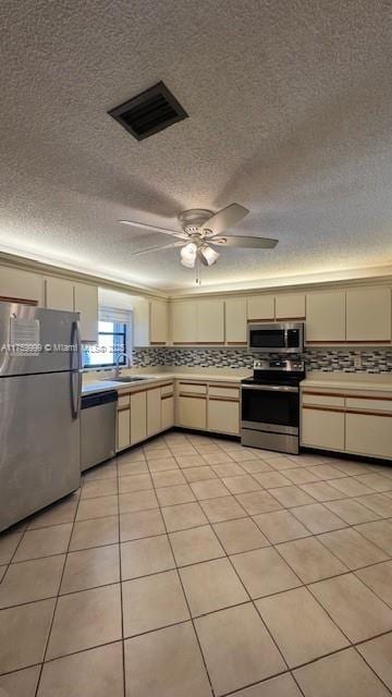 kitchen featuring tasteful backsplash, cream cabinetry, appliances with stainless steel finishes, and visible vents