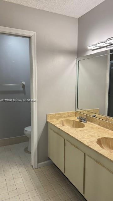 full bath with toilet, a textured ceiling, and a sink