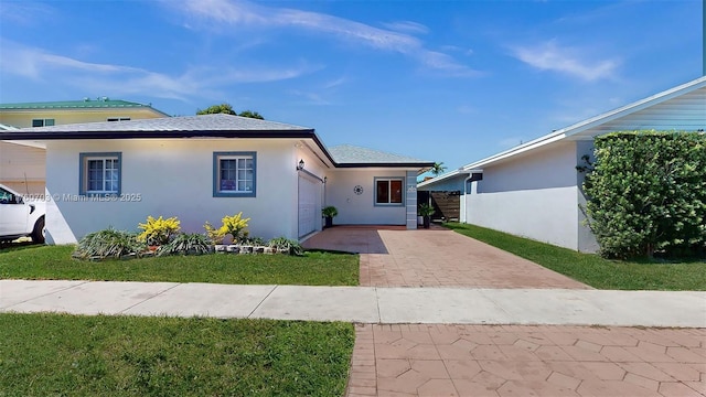 view of front facade with decorative driveway, a shingled roof, a front yard, and stucco siding