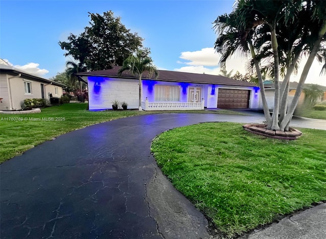 ranch-style house featuring a front lawn, an attached garage, and driveway