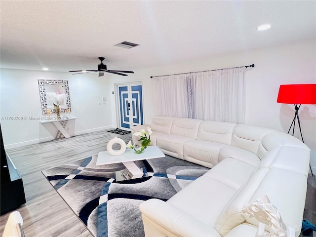 living area with visible vents, a textured ceiling, baseboards, and wood finished floors