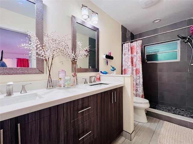 bathroom with a sink, tiled shower, toilet, and double vanity