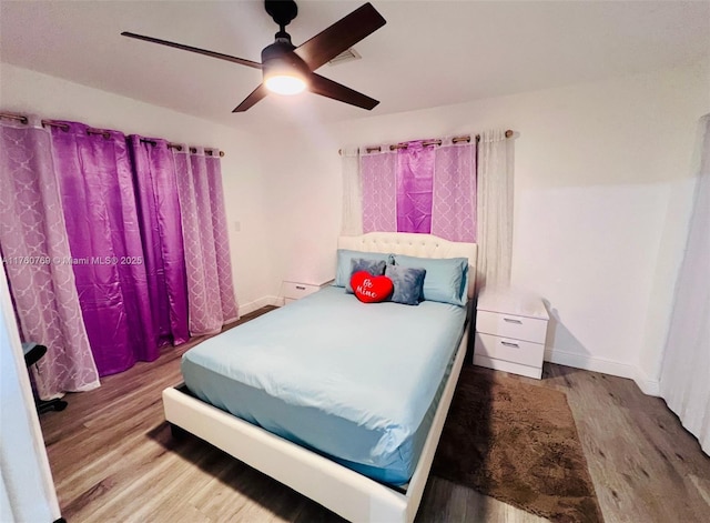 bedroom featuring wood finished floors, baseboards, and ceiling fan