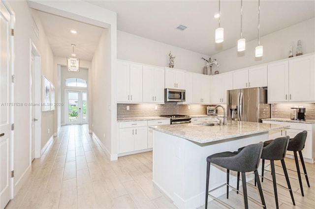 kitchen with a sink, stainless steel appliances, a kitchen breakfast bar, and tasteful backsplash