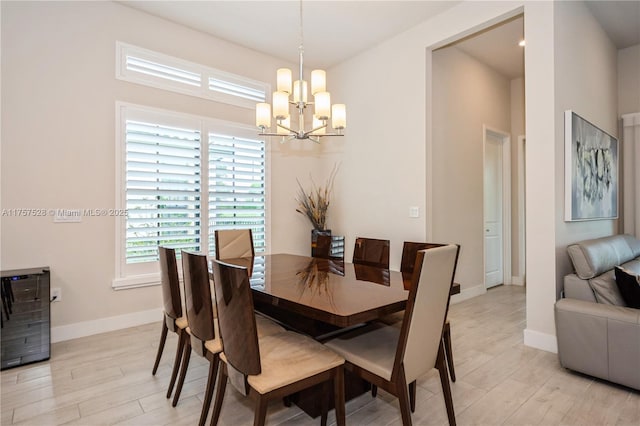 dining room with baseboards, light wood-type flooring, and an inviting chandelier