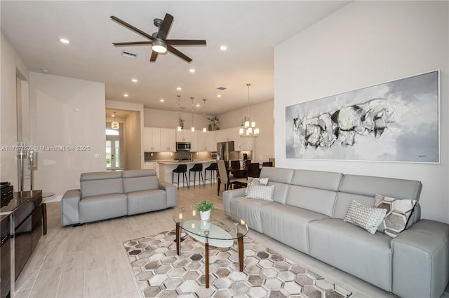 living area featuring recessed lighting, light wood-type flooring, and ceiling fan with notable chandelier