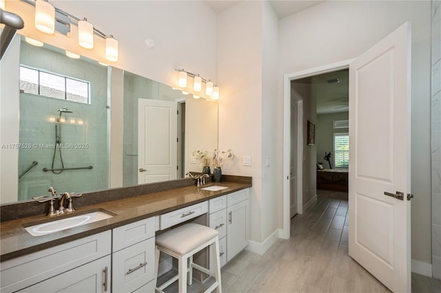 ensuite bathroom featuring double vanity, connected bathroom, tiled shower, and a sink