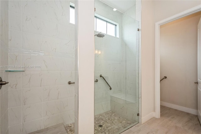 bathroom with wood finished floors, baseboards, and tiled shower