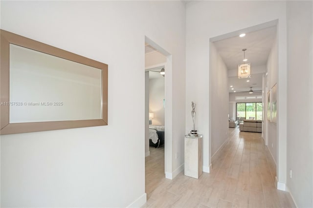 corridor featuring recessed lighting, baseboards, and light wood-style flooring