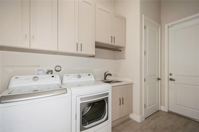 laundry area with baseboards, washer and clothes dryer, light wood-type flooring, cabinet space, and a sink