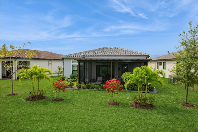 rear view of property with stucco siding, a tile roof, and a lawn