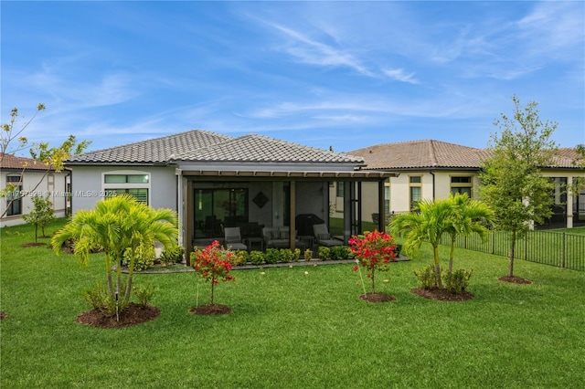 rear view of house featuring stucco siding, a tile roof, a lawn, and a sunroom