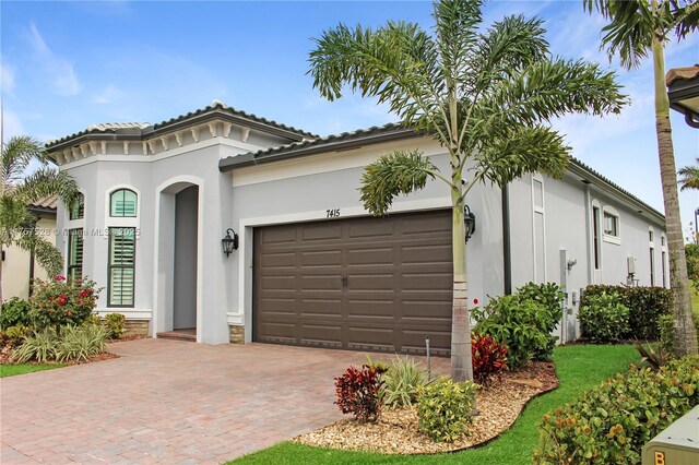 mediterranean / spanish house with stucco siding, an attached garage, and decorative driveway