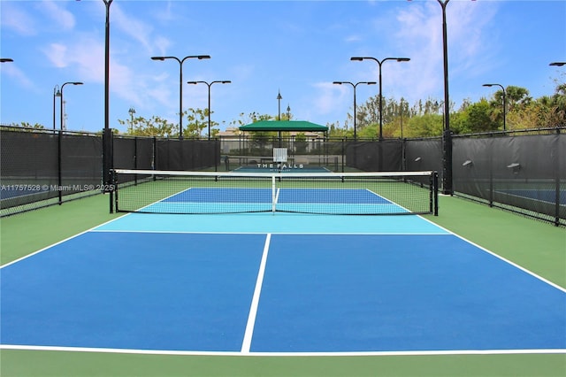 view of tennis court with community basketball court and fence