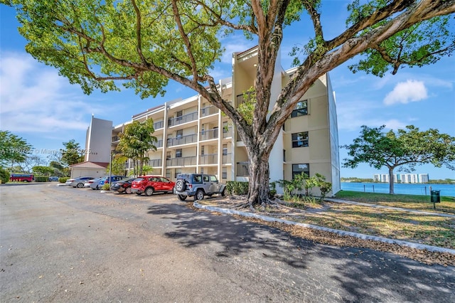 view of property with uncovered parking and a water view