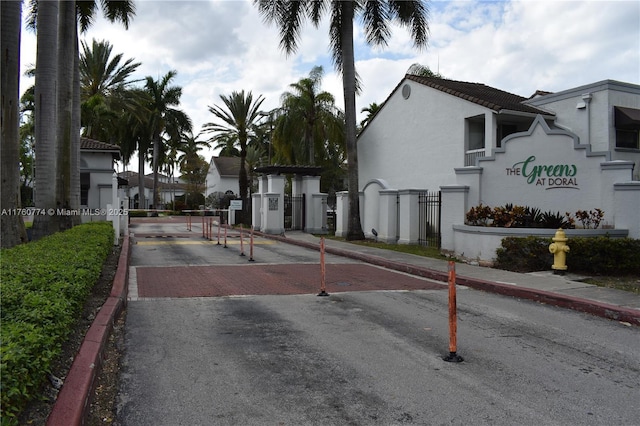 view of road with a gated entry, sidewalks, curbs, and a gate