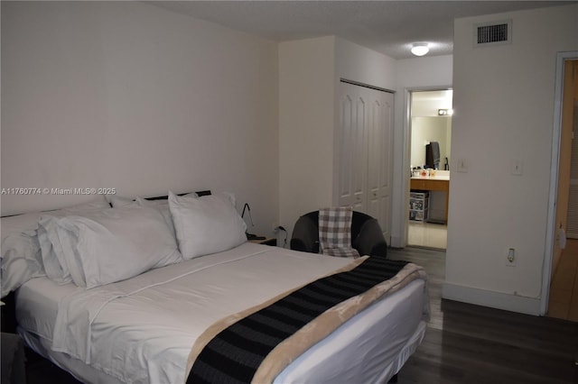 bedroom featuring wood finished floors, visible vents, a closet, and baseboards