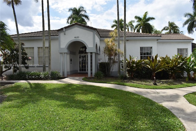 mediterranean / spanish home featuring stucco siding, a tile roof, and a front yard