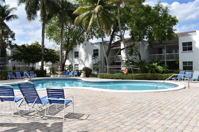 community pool with a patio and fence