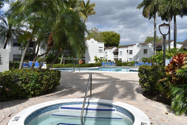 pool with a residential view and a hot tub