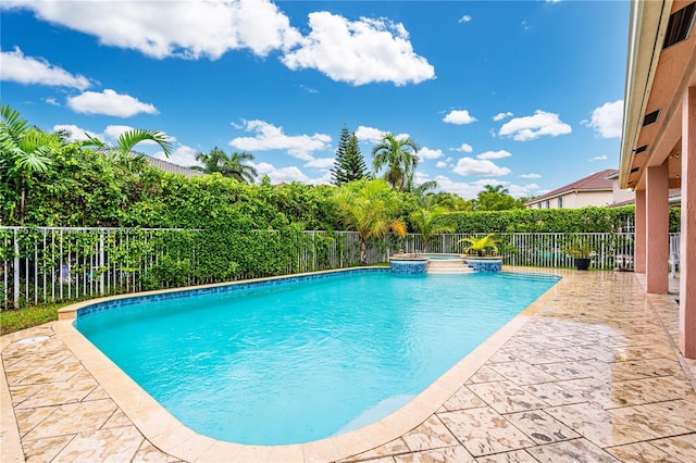 view of swimming pool featuring a fenced backyard, a pool with connected hot tub, and a patio