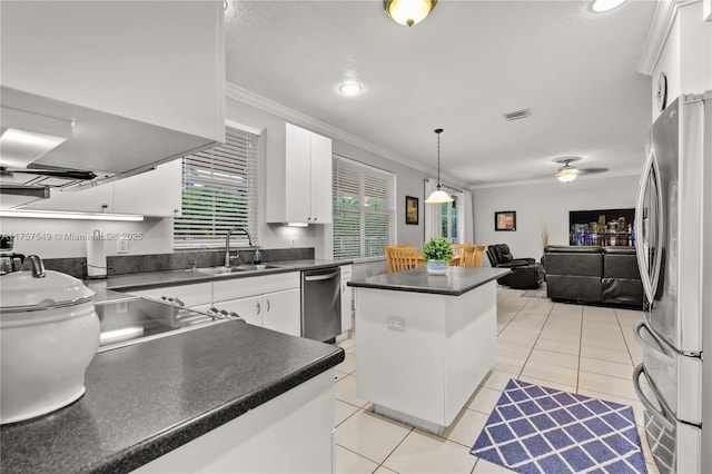 kitchen with light tile patterned floors, a sink, ornamental molding, stainless steel appliances, and dark countertops