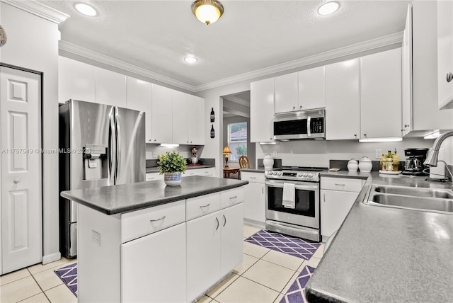 kitchen with light tile patterned floors, appliances with stainless steel finishes, a center island, and crown molding