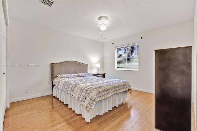 bedroom featuring light wood-type flooring, baseboards, and visible vents