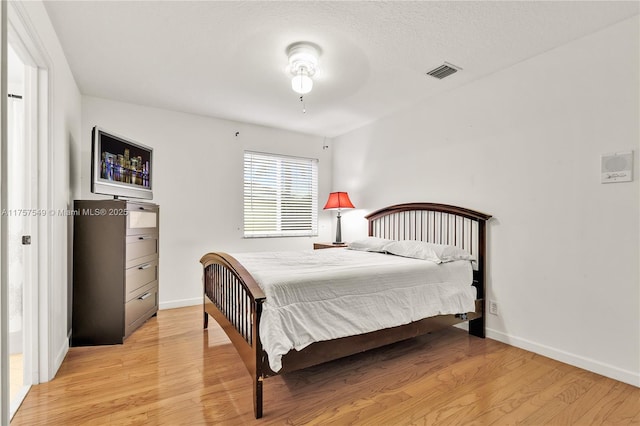 bedroom featuring visible vents, baseboards, and light wood-style floors