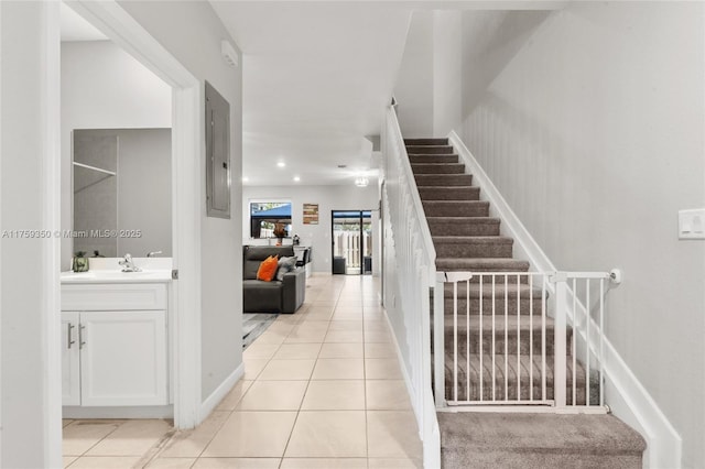 interior space with stairs, light tile patterned flooring, a sink, and electric panel