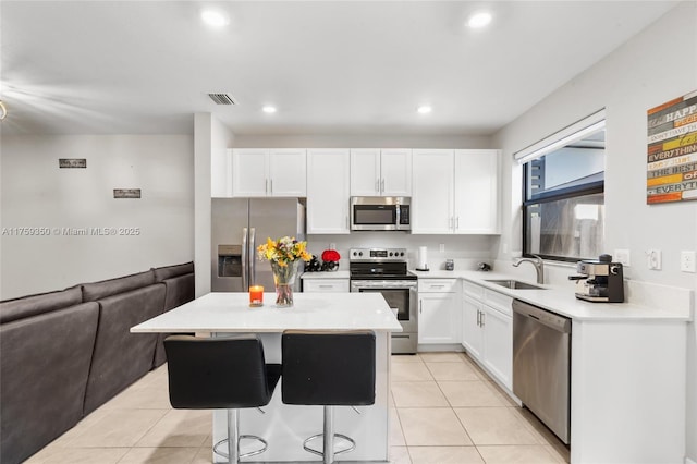 kitchen with open floor plan, a center island, white cabinetry, a sink, and appliances with stainless steel finishes