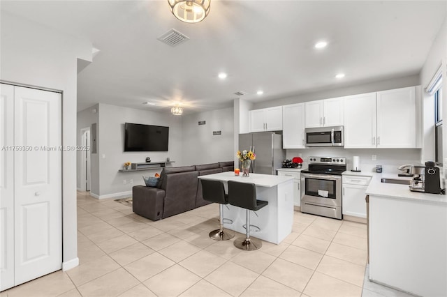 kitchen featuring visible vents, a center island, light countertops, open floor plan, and stainless steel appliances