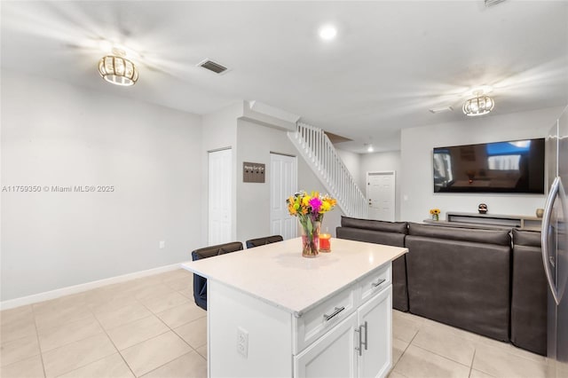 kitchen with visible vents, a center island, light tile patterned floors, light countertops, and white cabinetry