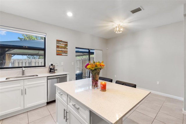 kitchen featuring visible vents, dishwasher, a sink, light tile patterned floors, and white cabinetry