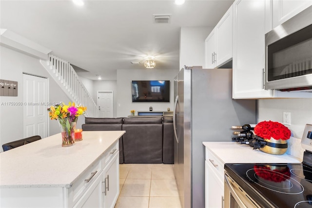 kitchen with white cabinets, light tile patterned flooring, light stone counters, stainless steel appliances, and visible vents