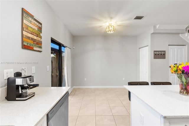 kitchen with stainless steel dishwasher, visible vents, baseboards, light stone counters, and light tile patterned floors